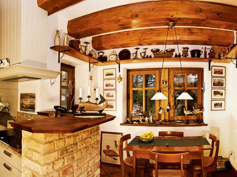 Der aus rustikalen Klinkern gemauerte Küchentresen passt perfekt zur Balkendecke.