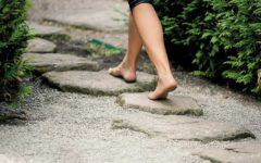 Nackte Füße laufen über einen Naturstein-Gartenweg.