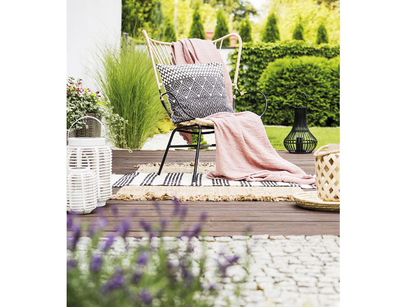 Terrassenplanung Kombination aus Hinzielen und Stein mit schickem Stuhl mit Plaid und Kissen