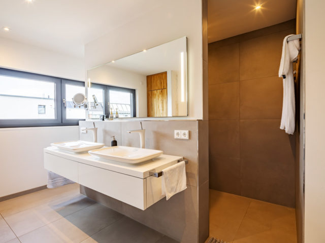 Satteldach modern 164 von Luxhaus Bad mit bodengleicher Dusche und WC hinter Vorwand mit Doppelwaschbecken