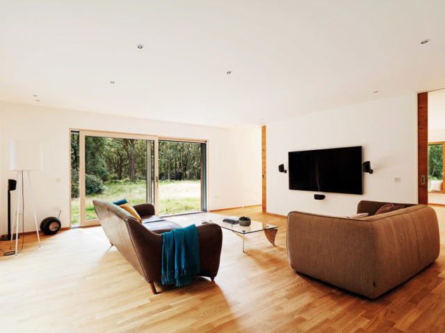 Baufritz Haus Lunn Wohnbereich mit Sofa und großem Sessel und Fernsehwand