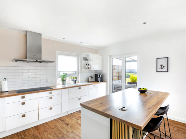 Küchenbereich mit weißen Fronten und Holzarbeitsplatte im Entwurf Karesa von Fingerhut Haus mit Zugang zur Terrasse