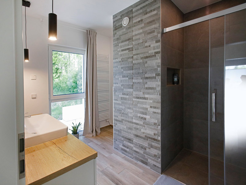 Danwood Park 102 individuell geplant Badezimmer mit bodentiefer Dusche mit dunklen Fliesen