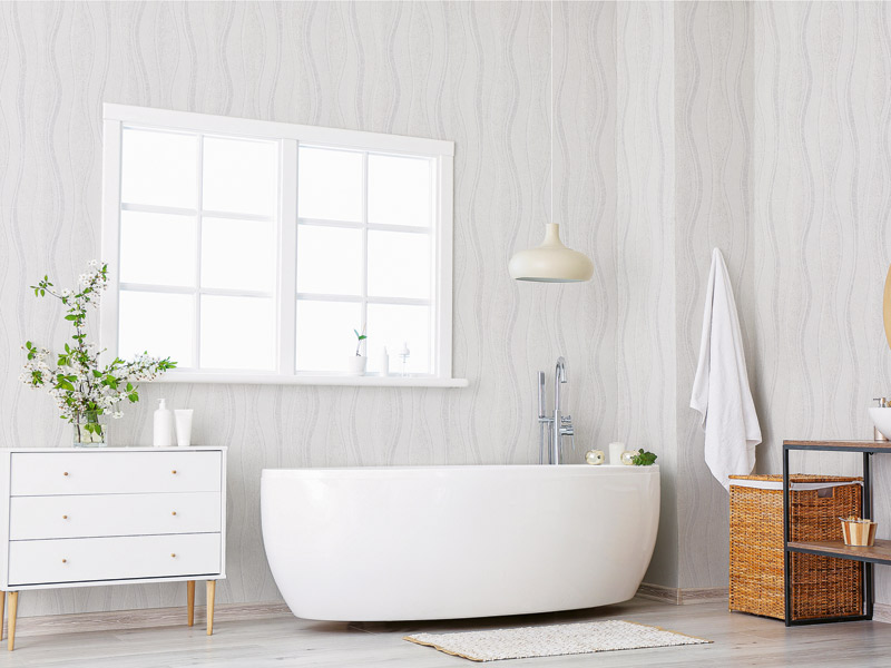 Badezimmer mit weißer Wanne vor einer Wand mit Strukturvliestapete