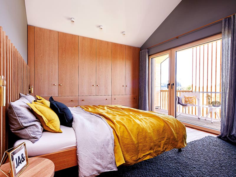 Baufritz Musterhaus Lichtblick Schlafzimmer mit Doppelbett und wandumfassendem Einbauschrank aus Holz