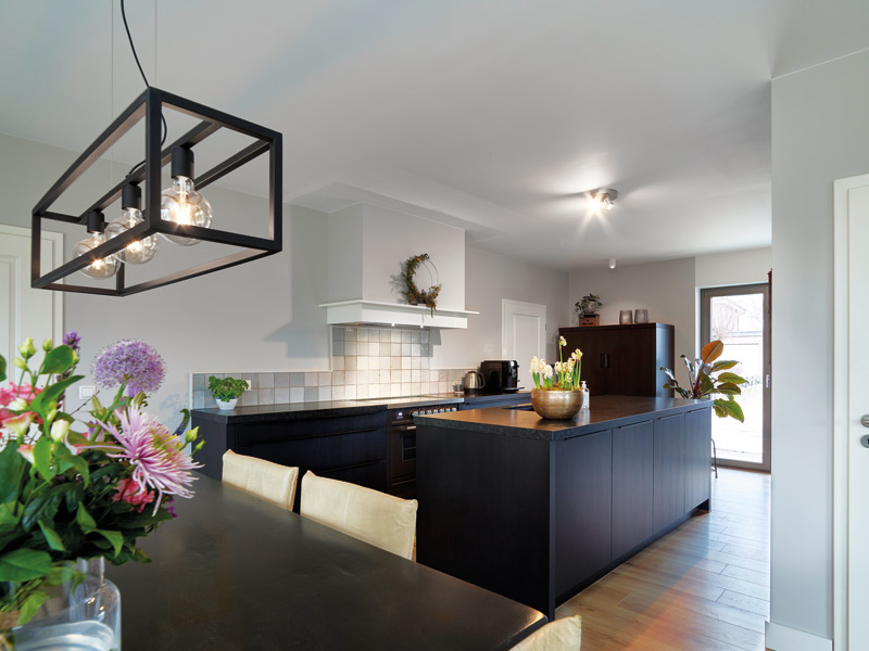 Gussek Haus Austum schwarze Inselküche mit hellem Fliesenspiegel im Hintergrund