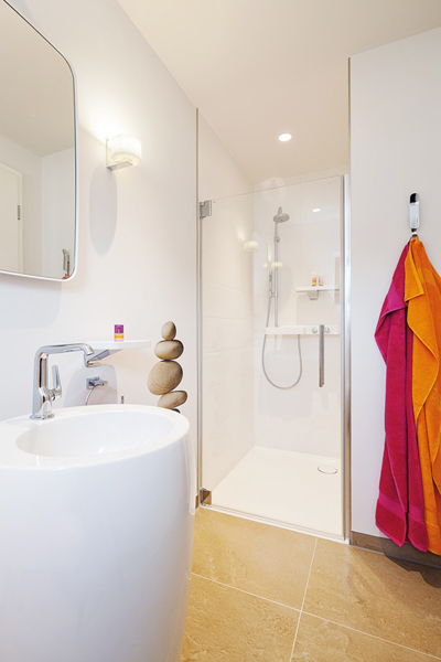 Helles Gästebad mit Dusche in der Ecke und hohem Standwaschtisch im Musterhaus Frame