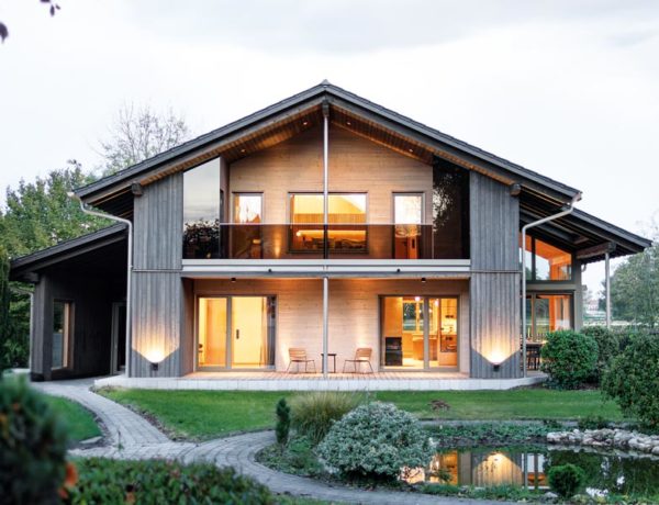Sonnleitner Musterhaus Starnberg Aussenansicht Gibelseite mit überdachter Terrasse und Balkon