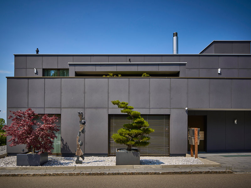 Design 253 von Frammelsberger Holzhaus eher zurückhaltender Eingangsbereich zur Straßenseite mit den dunklen Fassadenplatten