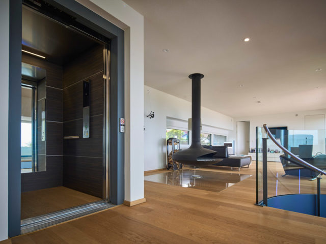 Design 253 von Frammelsberger Holzhaus Blick ins Obergeschoss mit hängendem Kamin und geöffnetem Aufzug