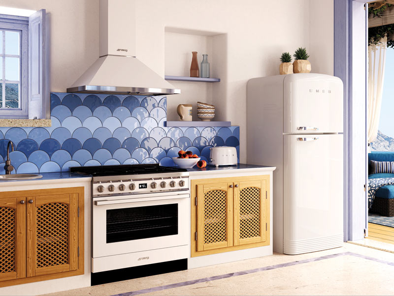 Kühlschrank von SMEG in weiß in mediterraner Küche mit blauen Fliesen stehend