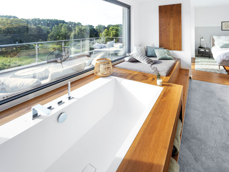 Wellnessbad zu Hause Badewanne unter einem Panoramafenster mit Ausblick ins Grüne