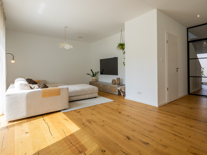 LUXHAUS Walmdach 169 Wohnbereich mit großer Couch und Fernseher an der Wand