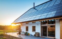 Einfamilienhaus mit Photovoltaik- und Solarthermiemodulen bei untergehender Sonne