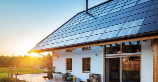 Einfamilienhaus mit Photovoltaik- und Solarthermiemodulen bei untergehender Sonne