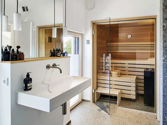 Bad mit großem Waschtisch und Spiegel darüber und einer eingebauten Holzsauna