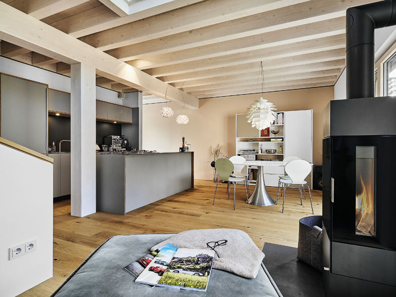 Offener Wohn-, Ess- und Küchenbereich im Haus Ullrich von Baufritz mit sichtbaren Deckenbalken