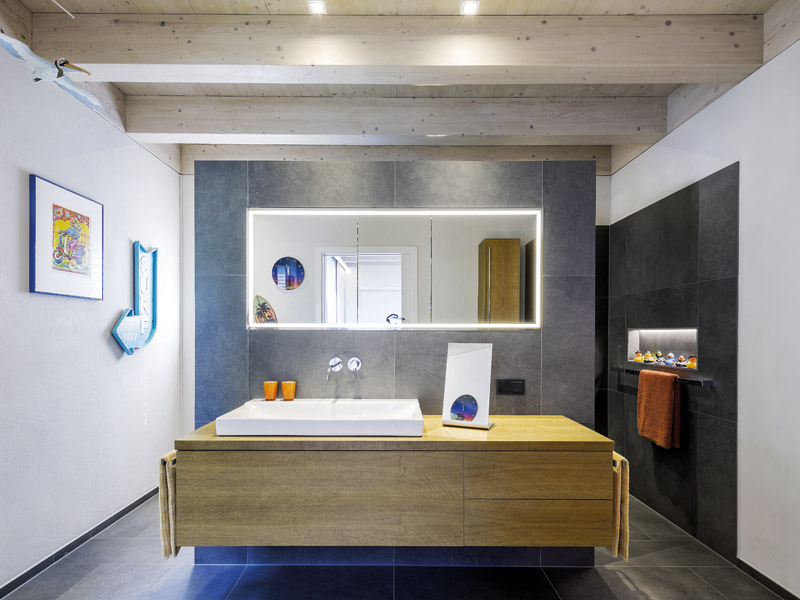 Badezimmer Wandscheibe mit großem Waschtisch und Spiegel und sichtbaren Holzbalken an der Decke
