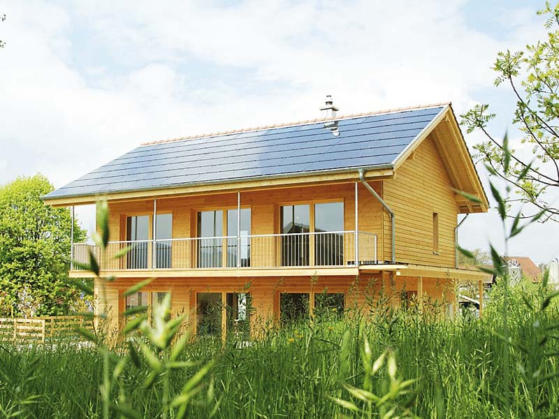 Modernes Holzhaus mit modernem Dach mit Photovoltaikmodulen mitten im Grünen