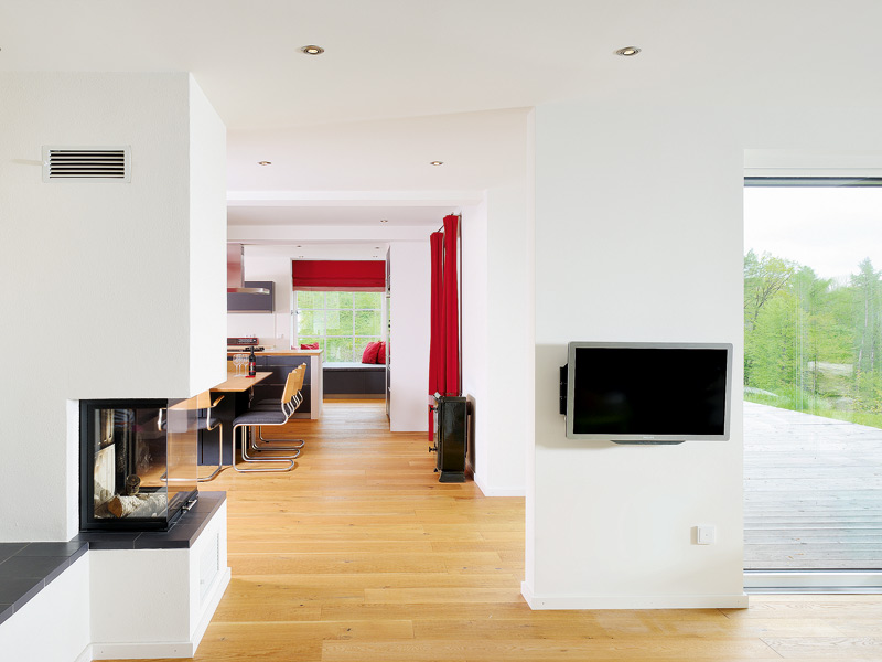 Wohnbereich mit Kamin und Fernseher und Blick in den Essbereich in einem Einfamilienhaus.