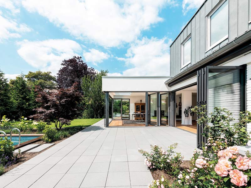 Haus mit geöffneten Glas-Faltwänden zur Terrasse und zum Pool.