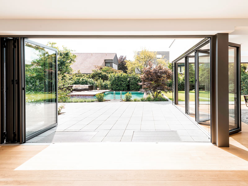 die geöffneten Glas-Faltwände zur Terrasse und anschließendem Pool hin erweitern den Wohnbereich im Sommer.