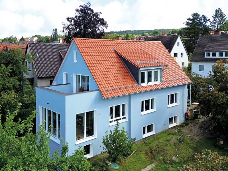 Älteres Satteldachhaus neu gedämmt, verputzt und gestrichen in Hellblau.