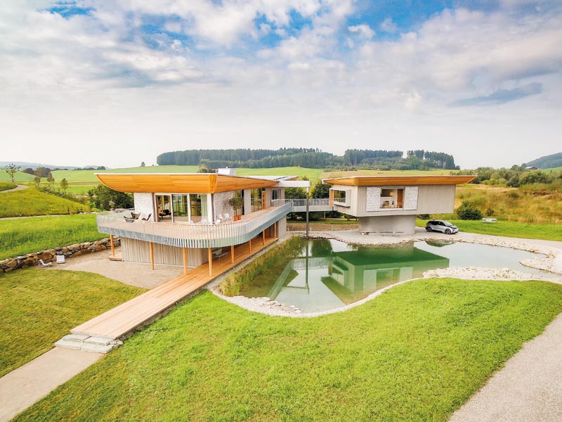 Vorderansicht vom Musterhaus Haussicht mit einem Teich davor.