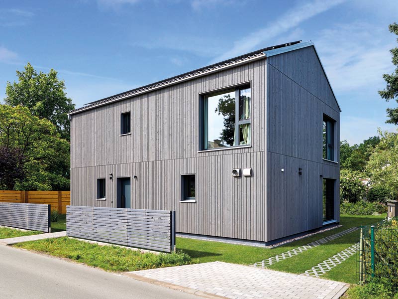 my smart green home individuell von Baufritz Aussenansicht zur Straße mit passendem Holzzaun und nur einem großen Fenster zur Straße hin