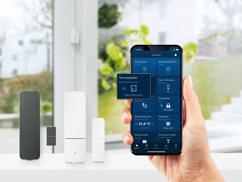 Auf einem Smartphone, gehalten in einer rechten Hand lassen sich verschiedene Dinge des Smart Homes erkennen und überprüfen.