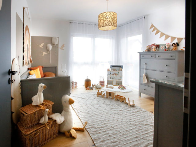 Kinderzimmer mit viel Holz, Holzspielzeug und hellen Kuscheltiere eingerichtet.