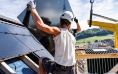 Zwei Arbeiter montieren Indach-Module für ein Solardach, eine vollflächige Photovoltaikanlage auf dem Dach.