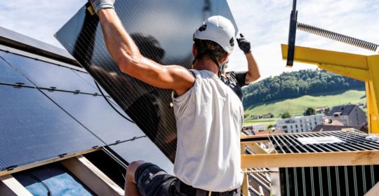 Zwei Arbeiter montieren Indach-Module für ein Solardach, eine vollflächige Photovoltaikanlage auf dem Dach.