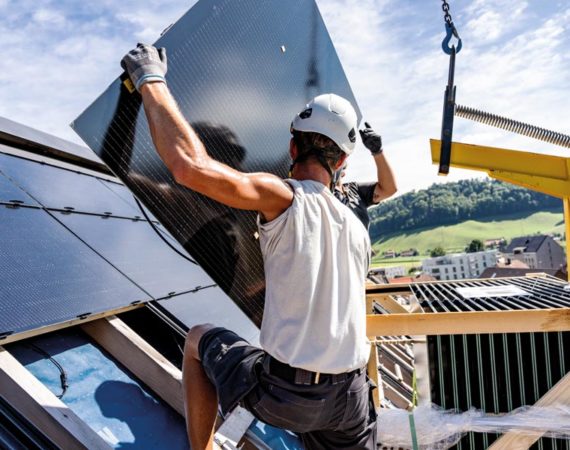 Zwei Arbeiter montieren Indach-Module für ein Solardach, eine vollflächige Photovoltaikanlage auf dem Dach.