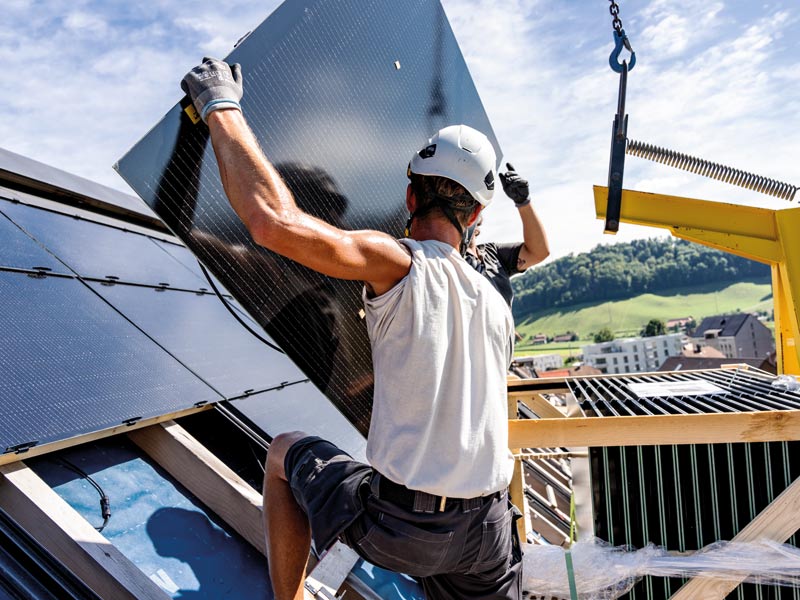 Zwei Arbeiter montieren Indach-Module für ein Solardach, eine vollflächige Photovoltaikanlage auf dem Dach.